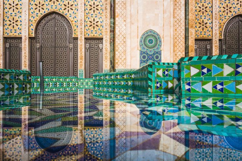 view of Hassan II mosque's big gate reflected on fountain water - Casablanca - Morocco