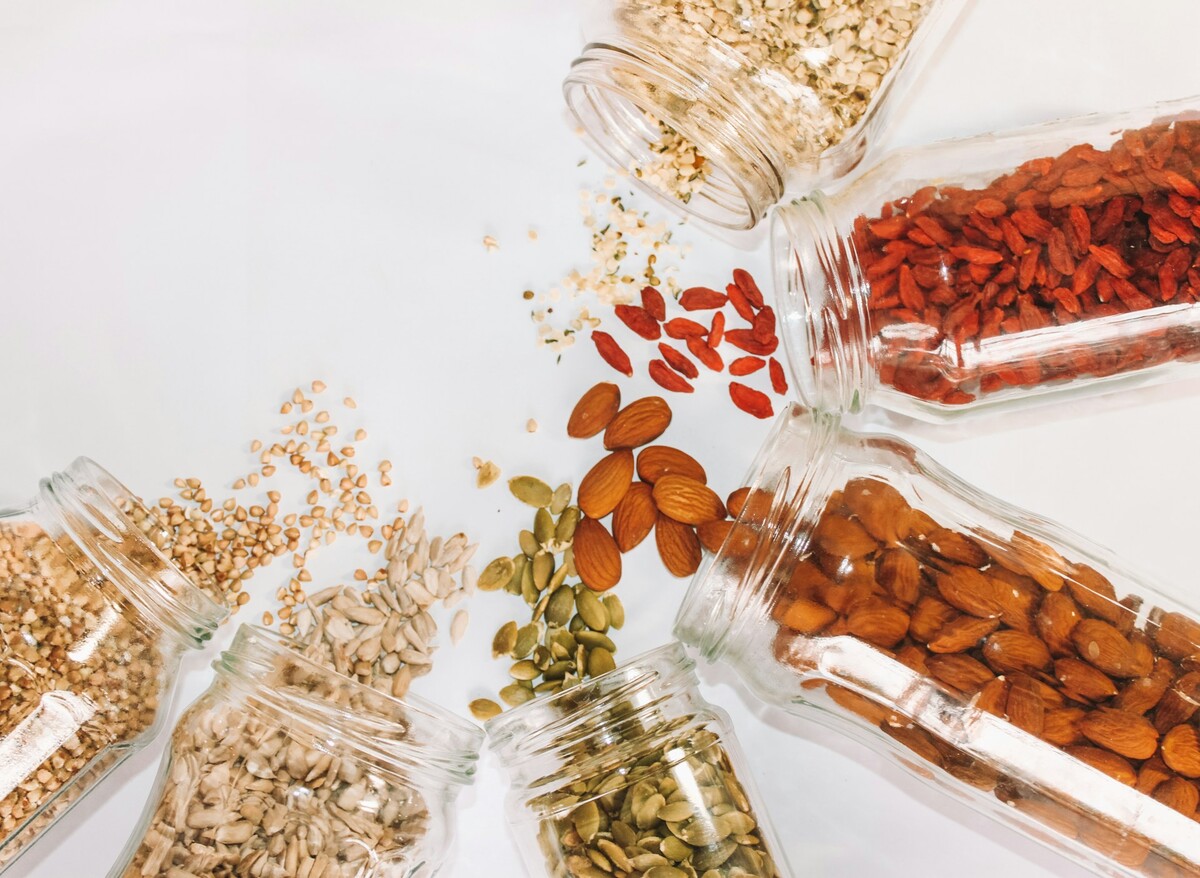 Domestic healthy vegetarian dry food storage organization on shelf at kitchen cupboard. Comfortable neatly keeping arrangement in glass containers oat flakes, wheat flour, sugar, pasta, nuts, rice