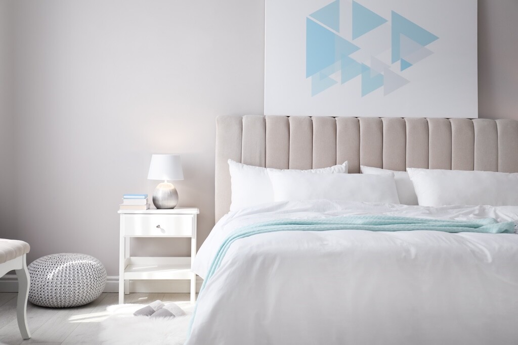 Cozy bed with soft linens in light room